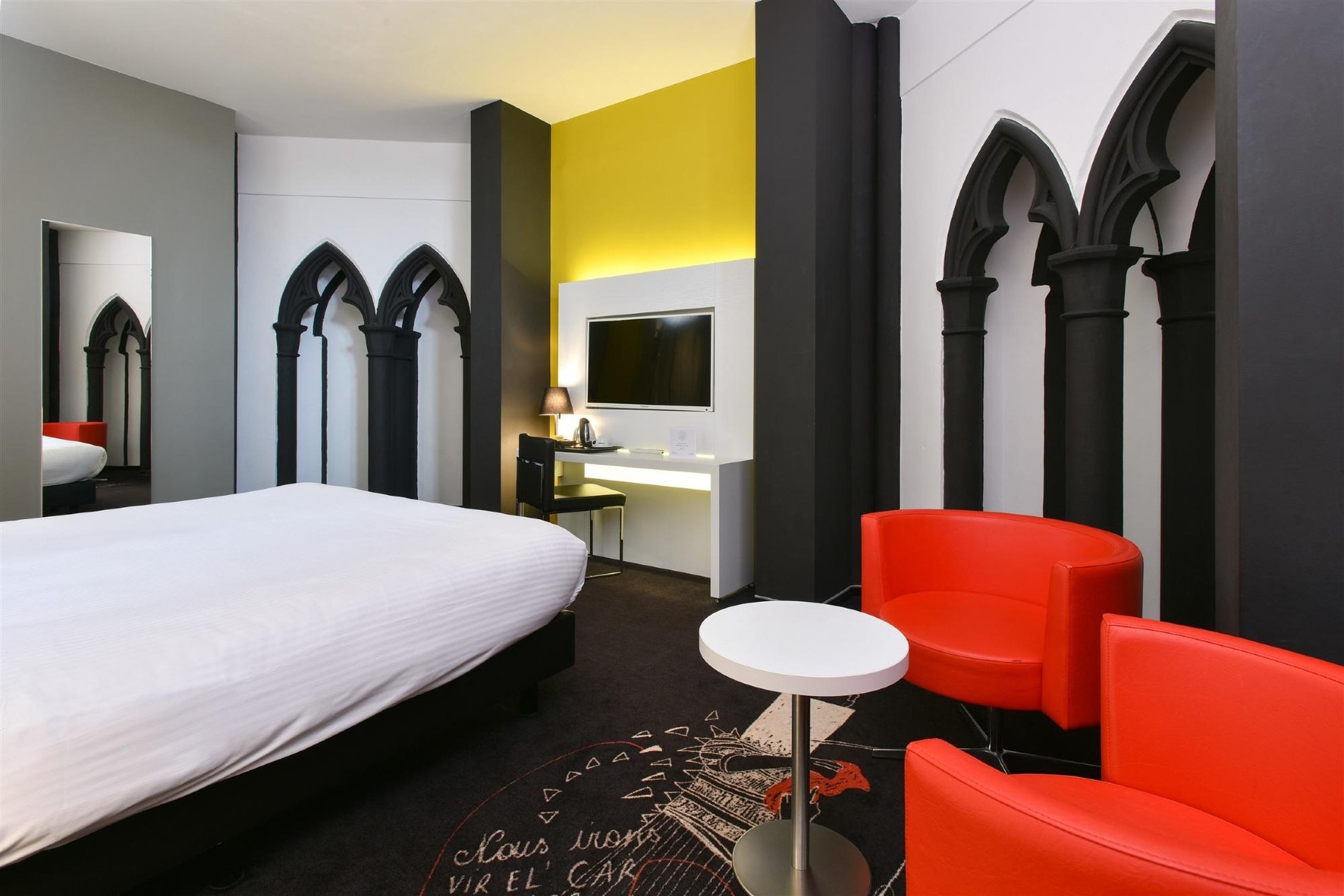 Charming Plus Zimmer mit roten Sesseln und gotischen Fenstern.