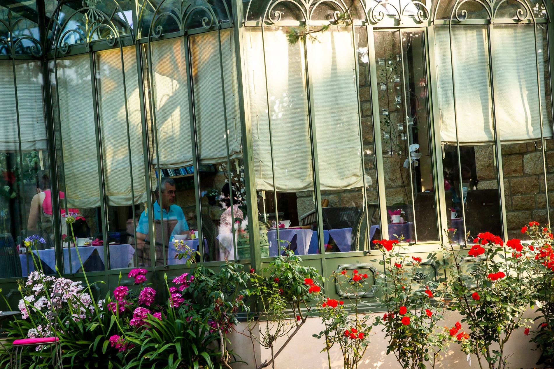 Terrasse fleurie devant la véranda de l'Hôtel La Ramade, symbolisant un espace extérieur accueillant et coloré.