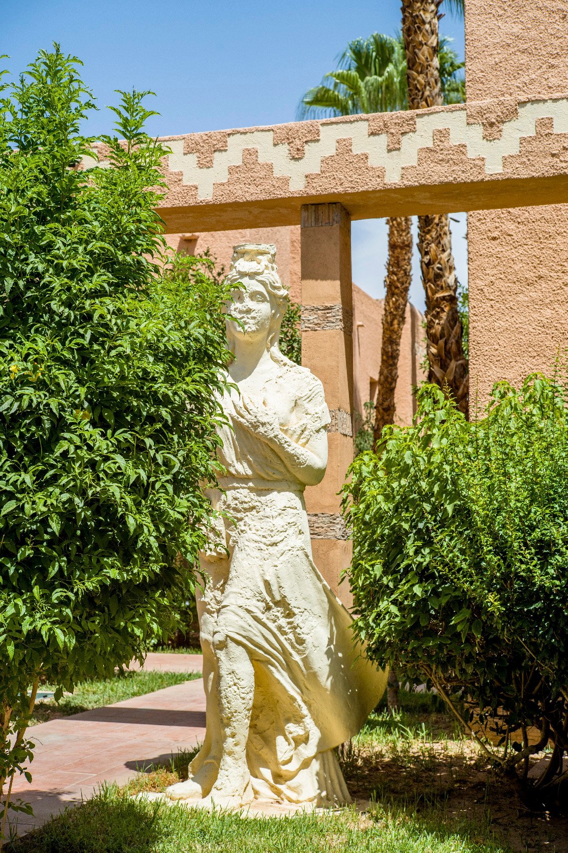 Le Berbère Palace, Façade ocre du Berbère Palace entourée de verdure et de sculptures