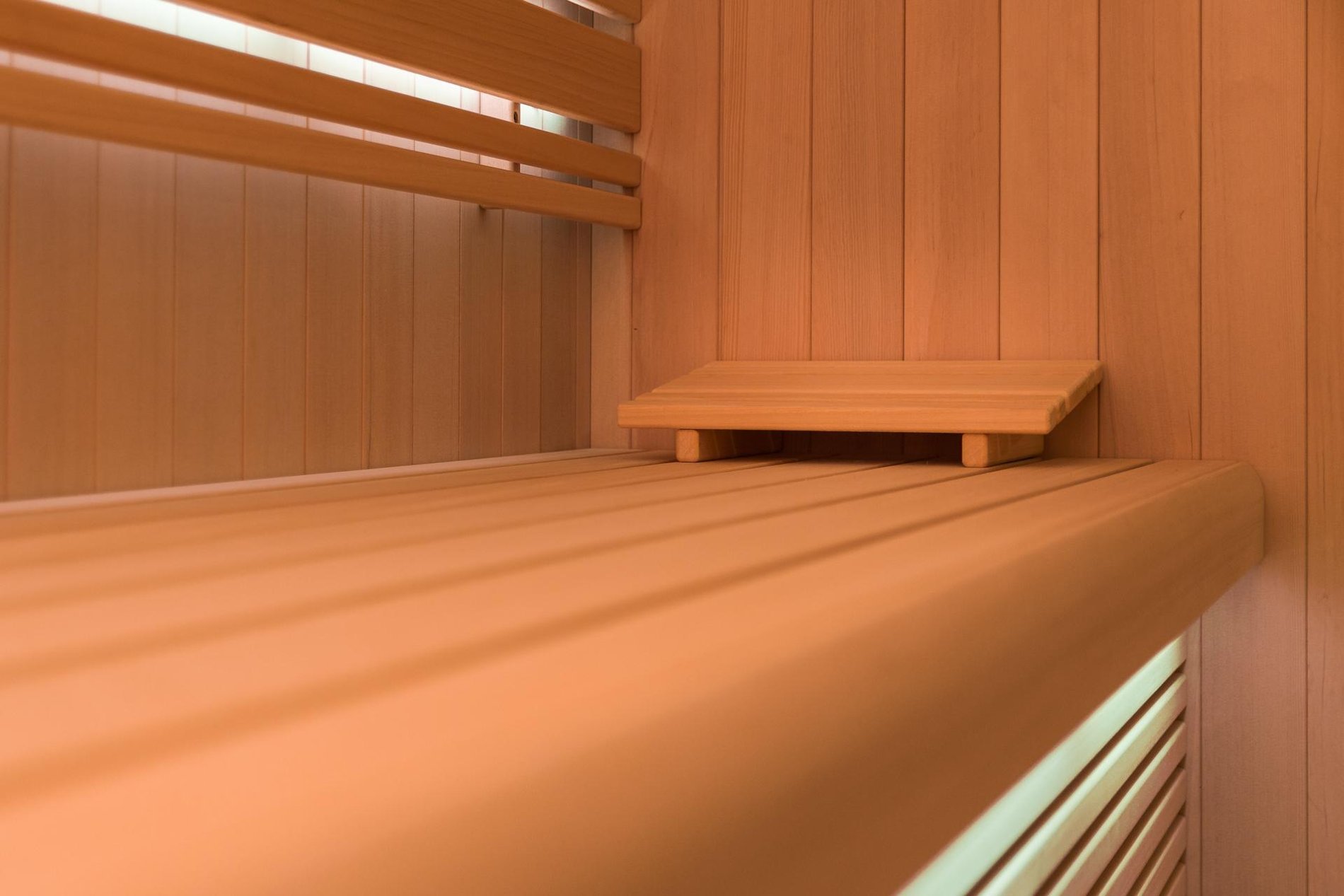 Houten bank in een sauna met een warme sfeer en gedempt licht.